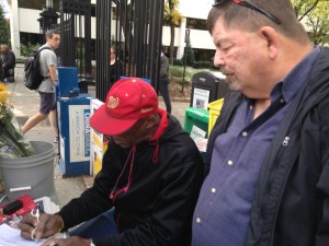 John with street vendor signing our petition.